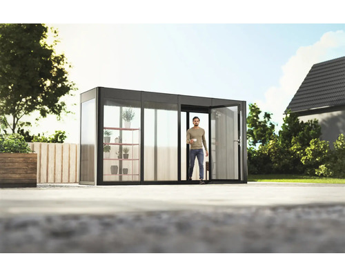 Gewächshaus SunGarden Select 4.1 Polycarbonat 10 mm 443 x 129 cm anthrazit Modernes Gartenhaus mit Mann im Eingang, Pflanzenregal und viel Tageslicht.