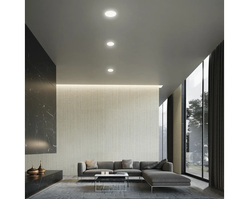 Salon avec spots encastrés au plafond, canapé et baie vitrée