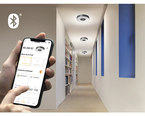 Smartphone-App steuert Deckenleuchten in einem Flur mit Bücherregal