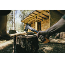 Une hache fend du bois sur un billot à l''extérieur.