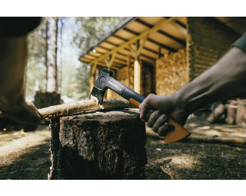 Une hache fend du bois sur un billot à l''extérieur.
