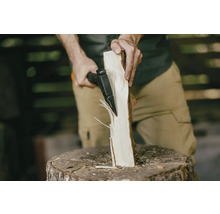 Une personne fend une bûche avec une hache sur un billot.