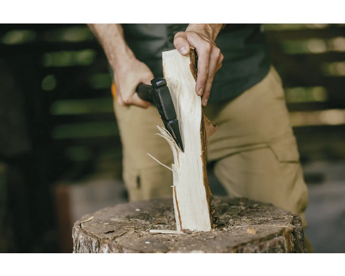 Une personne fend une bûche avec une hache sur un billot.