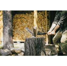 Homme fendant du bois avec une hache Fiskars sur un billot