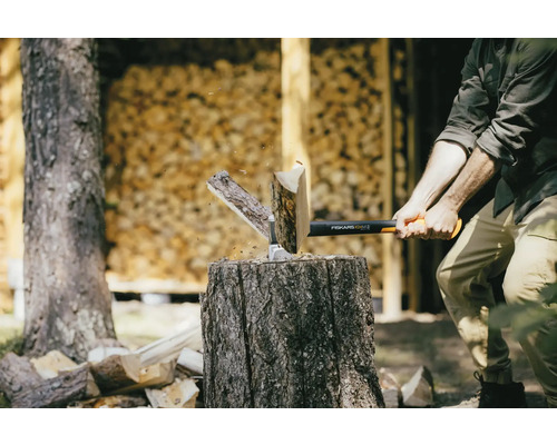 Homme fendant du bois avec une hache Fiskars sur un billot