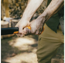 Gros plan d''une personne tenant une hache à fendre avec un manche orange pour fendre du bois.