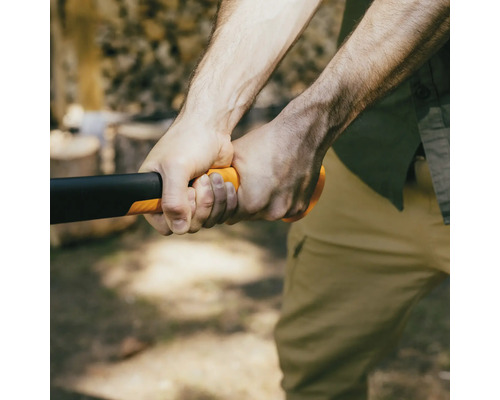 Gros plan d''une personne tenant une hache à fendre avec un manche orange pour fendre du bois.