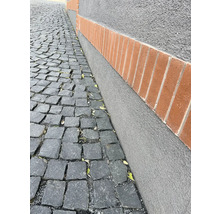 Pflastersteine und eine verputzte Wand mit Ziegelsteinen