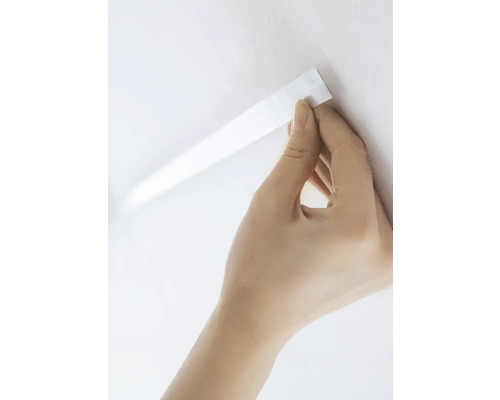 Main fixant du ruban adhésif au mur