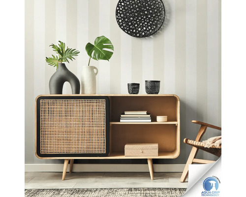 Buffet en bois avec porte en rotin devant un mur rayé