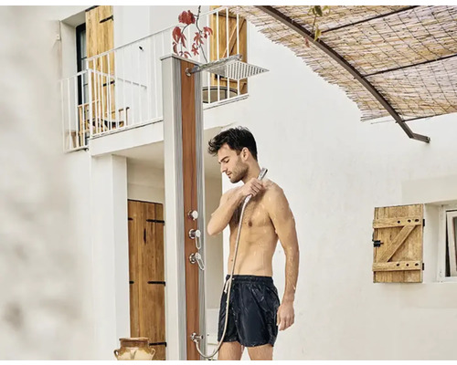 Homme sous une douche extérieure dans le jardin.