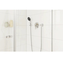 Moderne Duschkabine mit Armatur und Handbrause vor weissem Fliesenhintergrund.