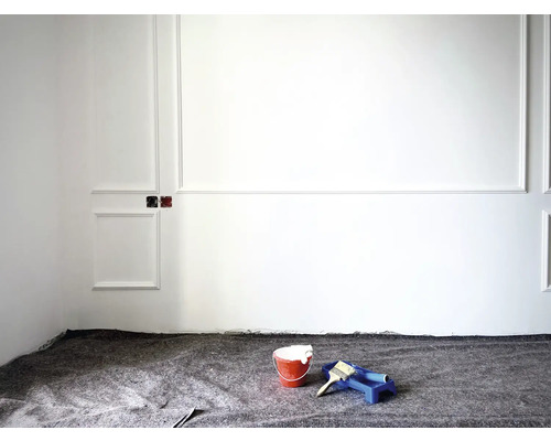 Travaux de rénovation dans une pièce avec un seau de peinture, un rouleau à peinture et une protection de sol