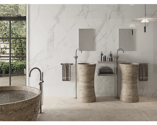 Badezimmer mit Badewanne, Waschbecken und Marmorfliesen für ein helles, geräumiges Ambiente.