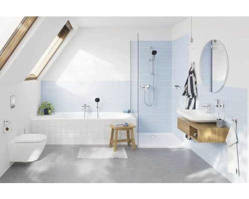 Salle de bains moderne avec baignoire, douche, lavabo et toilettes sous une fenêtre de toit.