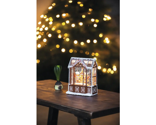 Maison en pain d''épices décorative avec neige et sapin de Noël en arrière-plan