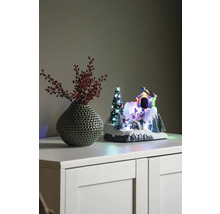 Paysage d''hiver décoratif avec maison, sapin de Noël et patineurs à côté d''un vase avec des baies rouges sur une armoire