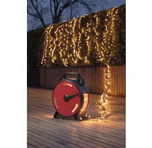 Scène avec une guirlande lumineuse sur un enrouleur éclairant un arbuste dans le jardin.