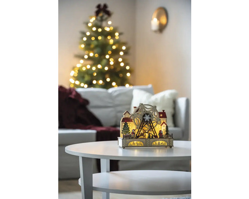 Dekorative Weihnachtsbeleuchtung mit Riesenrad auf einem Tisch in einem Wohnzimmer mit Weihnachtsbaum.