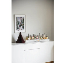 Dekoratives Weihnachtsdorf mit Zug auf einer weißen Kommode mit einem Bild von einem Zug an der Wand.