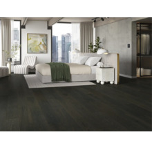 Schlafzimmer mit dunklem Holzboden, Bett und weissem Sessel