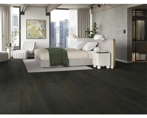 Schlafzimmer mit dunklem Holzboden, Bett und weissem Sessel