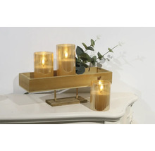 Bougies LED décoratives dans des récipients en verre sur un plateau en bois avec des plantes sur une table