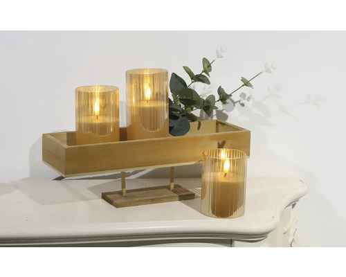 Bougies LED décoratives dans des récipients en verre sur un plateau en bois avec des plantes sur une table