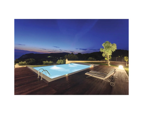 Piscine éclairée avec terrasse en bois et chaise longue au crépuscule