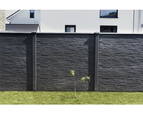 Mur en pierre avec poteaux en béton et herbe dans le jardin