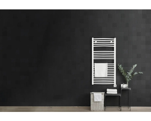 Salle de bain avec sèche-serviettes, panier à linge et table d''appoint devant un mur sombre