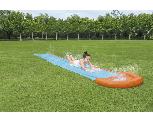 Mädchen rutscht auf einer Wasserrutsche im Garten