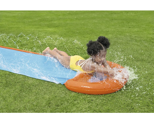 Mädchen rutscht auf einer Wasserrutsche im Garten.