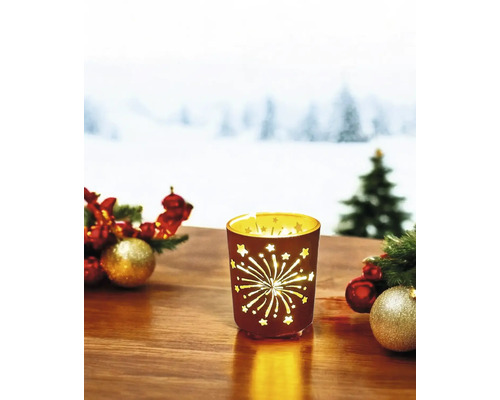 Dekoratives Windlicht mit Sternen- und Feuerwerksmuster auf einem Tisch mit Weihnachtsschmuck.