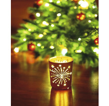 Photophore avec motifs d''étoiles et de feux d''artifice devant un arbre de Noël