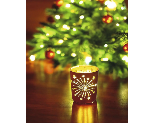 Windlicht mit Sternen und Feuerwerksmuster vor einem Weihnachtsbaum
