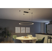 Esszimmer mit rundem Holztisch und darüber hängender, runder LED-Pendelleuchte.