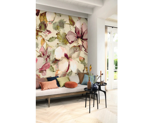 Wohnzimmer mit Wandtapete mit Blumenmuster, Sofa mit Kissen und Beistelltischen.