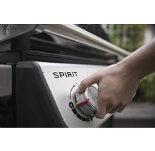 Detailaufnahme eines Gasgrills der Marke Spirit mit einer Hand, die den Bedienknopf dreht.