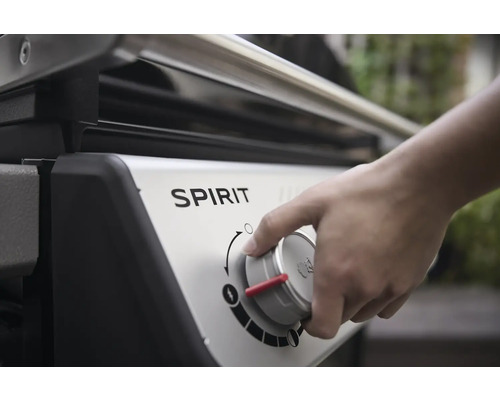 Detailaufnahme eines Gasgrills der Marke Spirit mit einer Hand, die den Bedienknopf dreht.