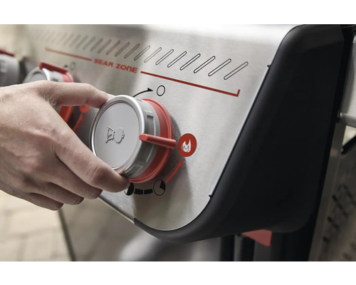 Nahaufnahme eines Gasgrill-Bedienfelds, das von einer Hand bedient wird.