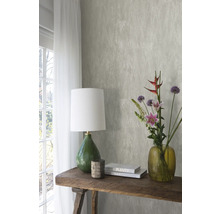 Dekoratives Interieur mit gemusterter Tapete, Tischleuchte, Blumen und Büchern auf einem Holztisch