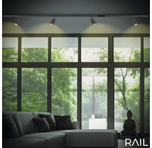 Wohnzimmer mit Schienensystemleuchte, Sofa und großem Fenster mit Blick ins Grüne