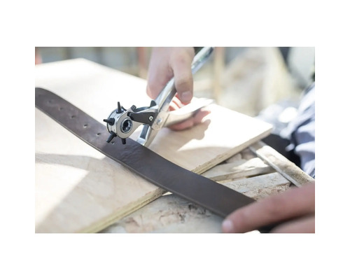 Une personne utilise une pince emporte-pièce revolver pour percer des trous dans une ceinture en cuir.