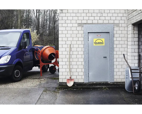 Szene mit Betonmischer auf einem Pritschenwagen, einer Schaufel und einer Schubkarre vor einem Gebäude