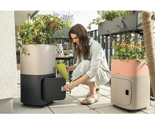 Frau öffnet Pflanzgefäss mit Stauraum auf dem Balkon