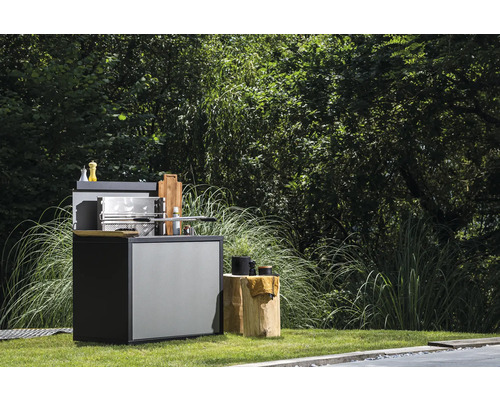 Grillküche im Garten mit Grill und Zubehör auf einem Baumstumpf