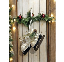 Dekorative Schlittschuhe mit Tannengrün, Weihnachtskugeln und Lichterkette als Wanddekoration.
