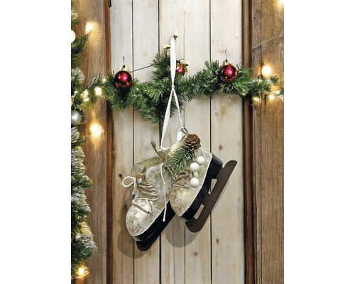 Dekorative Schlittschuhe mit Tannengrün, Weihnachtskugeln und Lichterkette als Wanddekoration.