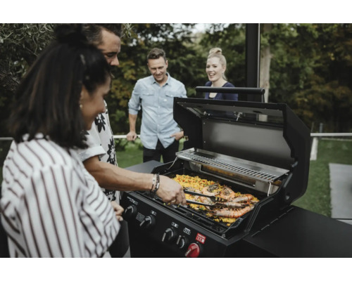Gruppe von Personen grillt Garnelen auf einem Gasgrill im Freien